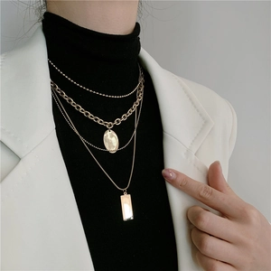 Detailed view of layered gold titanium steel necklaces with geometric pendants on model