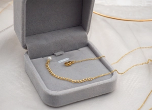 Macro detail of the golden lobster clasp and adjustable tail chain of the pearl necklace