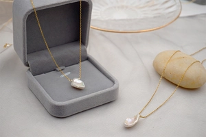 Detailed view of Baroque pearl necklace on a velvet jewelry box and satin fabric