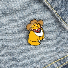 Detail of an enamel pin featuring a cute ginger cat wearing a cowboy hat on denim fabric