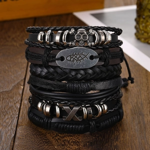 Macro detail of stacked black braided leather bracelets with skull and fishbone metal charms