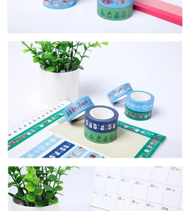 Detailed view of Christmas themed washi tape with snowman and tree patterns on a notebook