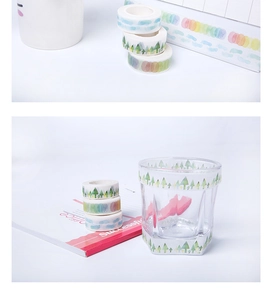 Detail of Christmas washi tape with forest and cloud patterns on glass and notebook