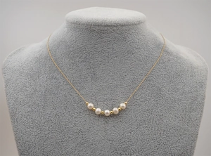 Detail of freshwater pearl necklace with gold beads on a model's neck for layering