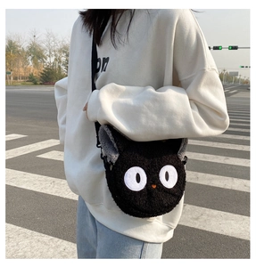 Detail of cute black plush cat cross-body bag featuring embroidered eyes and long strap