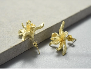 Macro shot of 3D iris flower stud earrings in matte gold finish with petal details