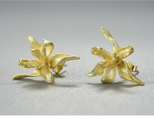 Macro detail of gold iris flower earrings with matte brushed metallic texture