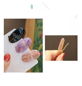 Detailed view of three cat-shaped hair clips in black, purple, and pink marble patterns