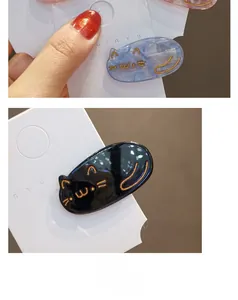 Close-up of cat-shaped hair clips in blue marble and black finishes with gold details