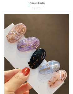Detail of five cute cat-shaped hair clips in marbled acetate with golden facial engravings