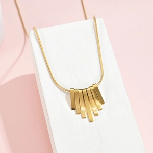 Detail of a minimalist gold bar necklace with fan-shaped geometric pendant on a snake chain