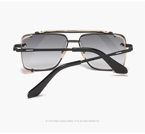 Detail of textured black sunglasses with golden metal bridge and gradient grey lenses