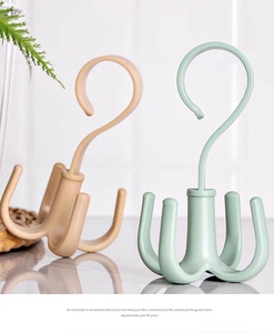 Detail of creative rotating 4-claw hangers in beige and green for organizing scarves and bags