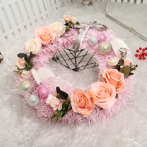 Pink Christmas wreath with roses, festive ornaments, and Happy Every Day ribbon on plush rug