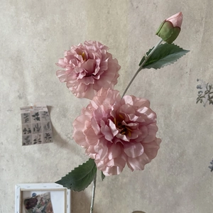 Detail of pink silk peonies with three heads and realistic green leaves in a home setting