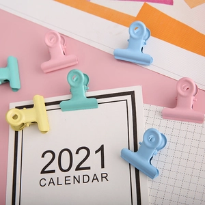 Colorful macaron metal binder clips set on pink background with 2021 calendar card
