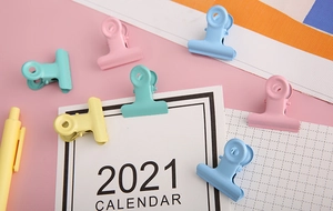 Flat lay of colorful 25mm metal binder clips with cute macaron pastel stationery