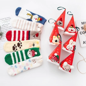 Detail of Christmas plush coral fleece socks with festive triangular gift box packaging