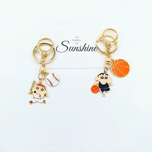 Close-up of baseball and basketball themed charms on golden keychains with cute characters