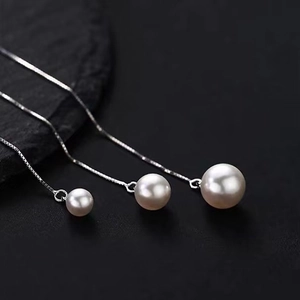Elegant S925 sterling silver tassel earrings with round white pearls on a black stone surface