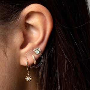 Gold star drop earrings and opal stud set with micro-pave crystals on model ear