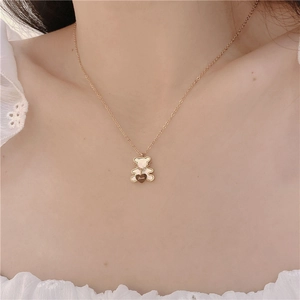 Detail of bear pendant necklace with white shell inlay and gold engraved heart charm
