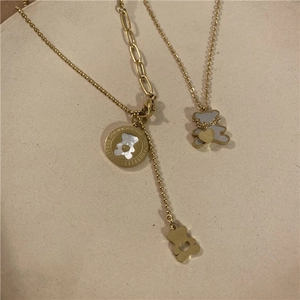 Detail of gold-tone bear necklaces with white mother of pearl inlay on a beige display