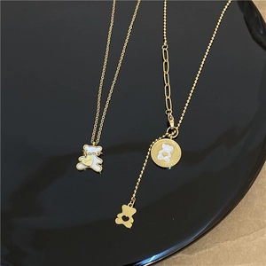 Detailed shot of gold titanium necklaces with white shell bear pendants on black display