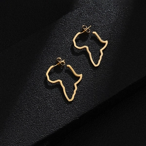 Detailed top view of gold Africa map earrings on textured black background