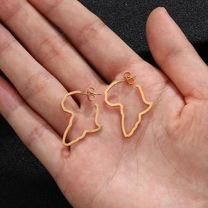Detailed view of hollow African map earrings in gold finish on hand with black background