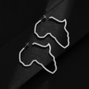 Macro shot of silver hollow Africa map earrings on a black textured background