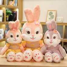 Detailed view of three plush rabbit dolls in pink and purple colors on a wooden table