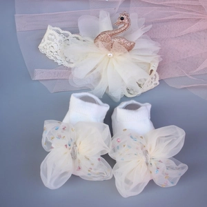 Detail of infant headband with swan crown and socks set with tulle bows and sequins