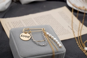 Detail of golden tassel safety pin brooch with Love pendant and freshwater pearls