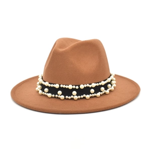 Detail of camel wool fedora hat featuring black ribbon band with white pearl embellishments