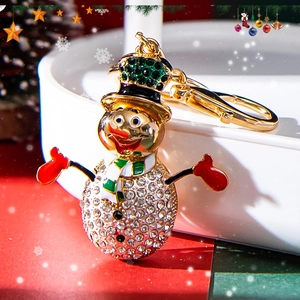 Sparkling snowman keychain with gold finish and rhinestones on festive Christmas background