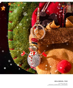 Detailed view of snowman keychain with white and red rhinestones on a gold metal base