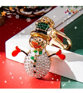 Close-up of a cute rhinestone snowman keychain with gold hardware and holiday scene