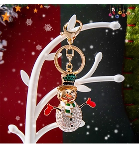 Close-up of a sparkling rhinestone snowman keychain with festive green hat and lobster clasp