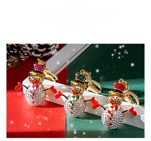 Close-up of sparkling rhinestone snowman keychains with festive enamel hats and scarves