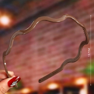 Detail of wave-shaped brown plastic headband featuring non-slip teeth, 13.7cm diameter