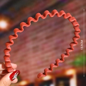Detail view of red wavy headband showing 13.5cm size dimension and matte finish