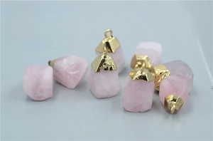 Macro shot of natural raw rose quartz stone pendant with gold-plated metal cap and ring