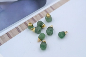 Detail of natural green raw stone pendant with gold plated cap on magazine background