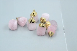 Close-up of raw rose quartz stone pendants with gold metal caps and natural textures
