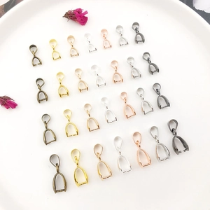 Macro detail of assorted sizes and colors of jewelry DIY pendant bails on white plate