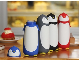 Close-up of four colorful penguin-shaped insulated water bottles on a wooden table