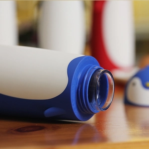 Macro shot of cute penguin glass water bottle with blue outer shell and inner glass liner