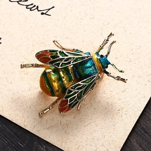 Macro shot of colorful enamel bee brooch with gold frame on textured background