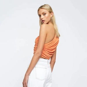 Detail view of the side and back of a sexy orange one-shoulder crop top for women